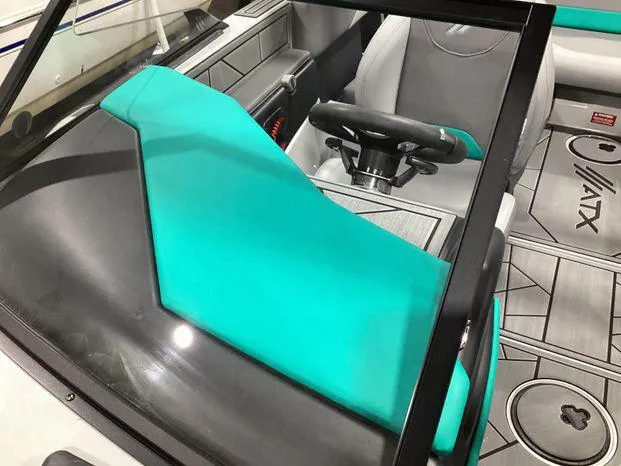 Slide: The Image of 2024 ATX Surf Boats 22ATX interior with teal and gray seating, steering wheel, and logo. - 10