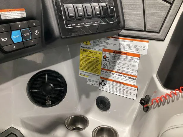 Slide: The Image of Control panel of 2024 ATX Surf Boats 22ATX with warning labels and cup holders. - 16