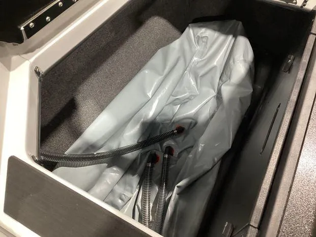 Slide: The Image of 2024 ATX Surf Boats 22ATX storage compartment with hoses and gray material. - 23