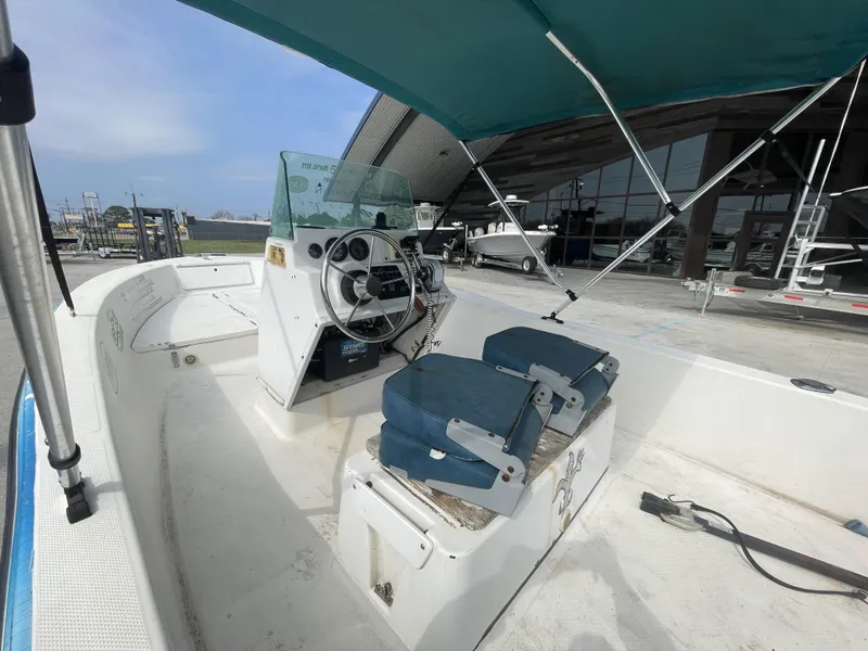 Slide: The Image of 1999 Bayliner 17cc boat interior with steering console and blue seats under canopy. - 6