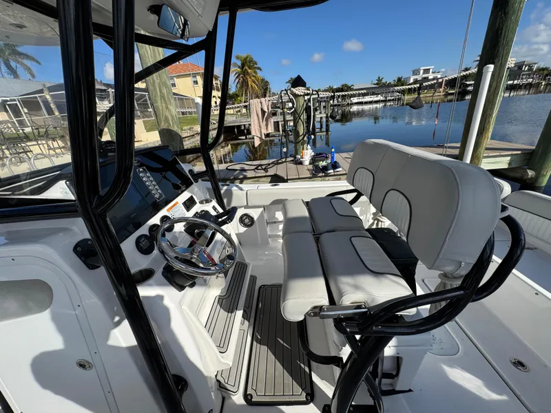 Slide: The Image of 2023 Sea Fox 268 Commander boat interior with helm and seating, docked by a waterfront. - 16