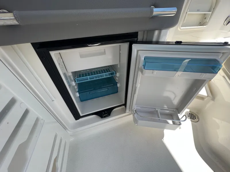 Slide: The Image of Open refrigerator on 2022 Sea Ray SLX 310 boat, showcasing interior storage space. - 15