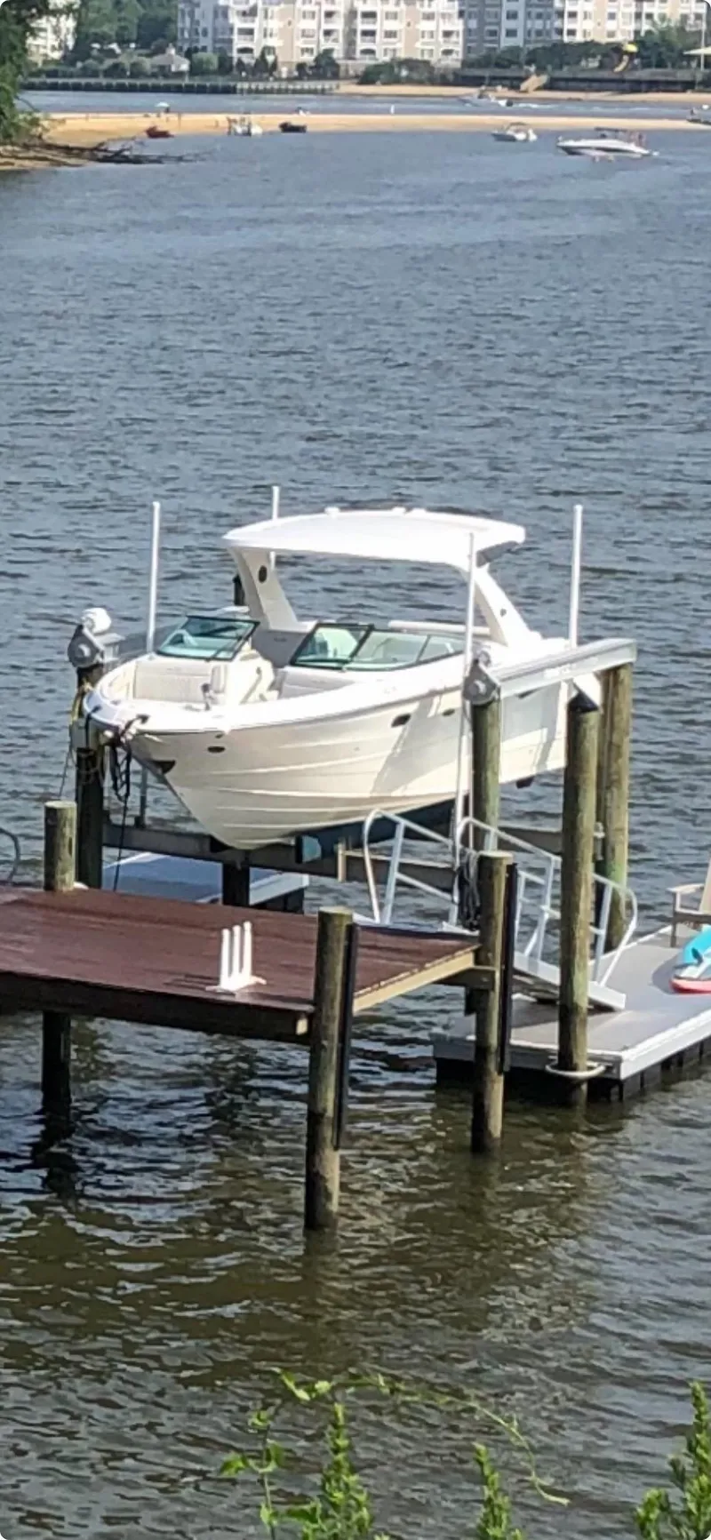 Slide: The Image of 2022 Sea Ray SLX 310 boat docked on a lift by the water. - 2