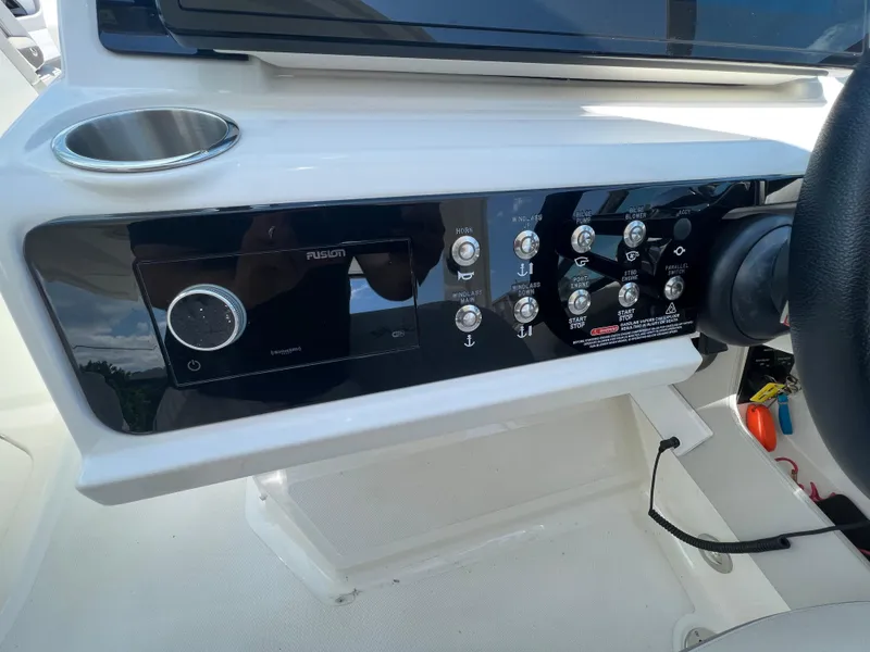 Slide: The Image of Control panel of 2022 Sea Ray SLX 310 boat with various switches and cup holder. - 21