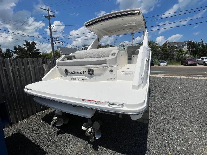Slide: The Image of 2022 Sea Ray SLX 310 boat, rear view, parked on gravel, under a blue sky. - 3
