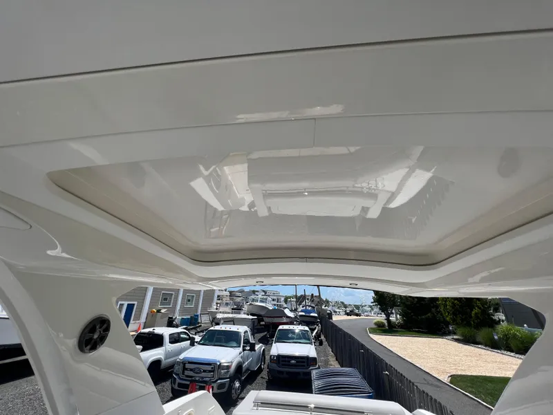 Slide: The Image of 2022 Sea Ray SLX 310 boat interior with sunroof, parked near trucks and houses. - 31