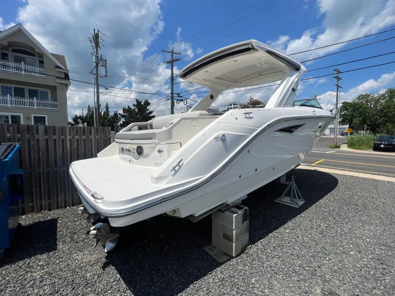 Slide: The Image of 2022 Sea Ray SLX 310 boat on display, parked on gravel under a blue sky. - 4