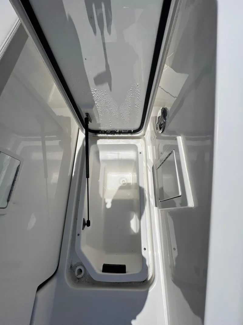 Slide: The Image of 2022 Sea Ray SLX 310 storage compartment with open lid, showcasing interior space. - 9