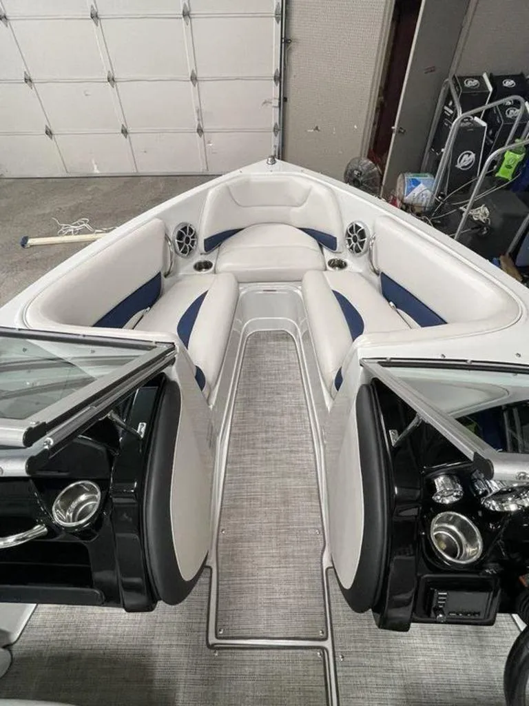 Slide: The Image of 2020 Crownline 205 SS boat interior with white and blue seating, speakers, and cup holders. - 10