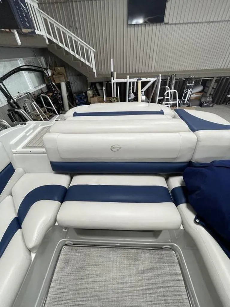 Slide: The Image of 2020 Crownline 205 SS boat interior with blue and white seating in a showroom. - 16