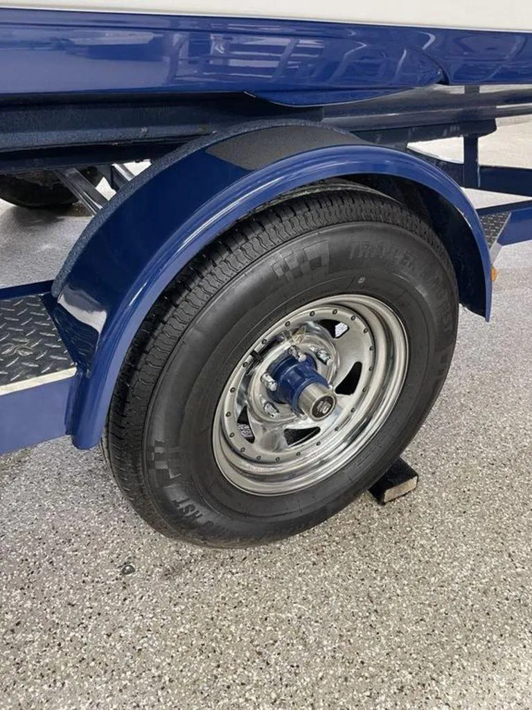 Slide: The Image of 2020 Crownline 205 SS boat trailer wheel with blue fender on concrete surface. - 22