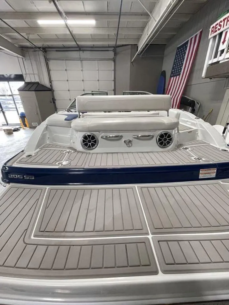 Slide: The Image of 2020 Crownline 205 SS boat in a garage, featuring a spacious deck and American flag. - 6