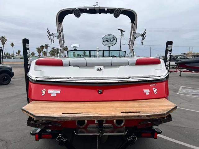 Slide: The Image of 2018 MasterCraft NXT22 boat, red and white, rear view in a parking area. - 7