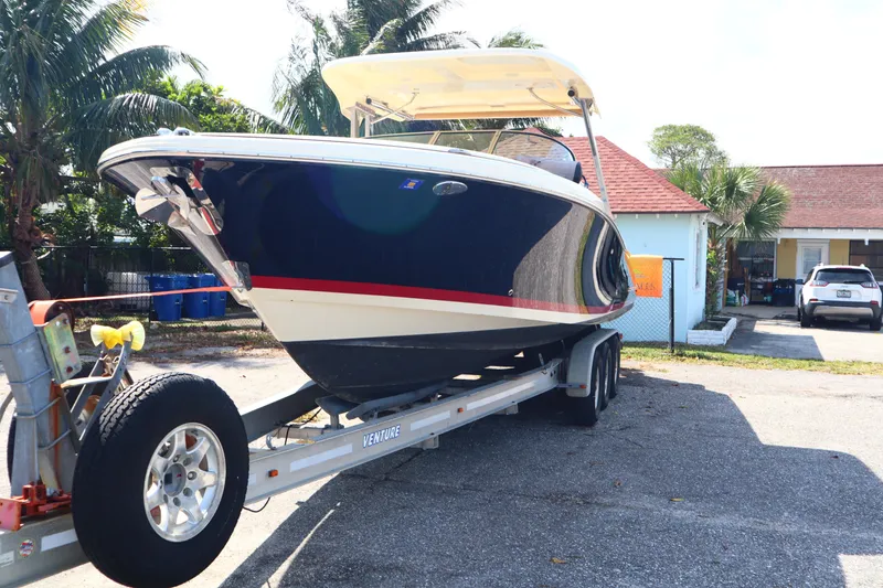 Slide: The Image of 2020 Chris-Craft Calypso 30 boat on trailer, parked near tropical setting. - 2