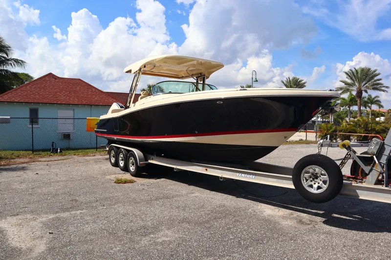 Slide: The Image of 2020 Chris-Craft Calypso 30 boat on a trailer, parked outdoors under a blue sky. - 3