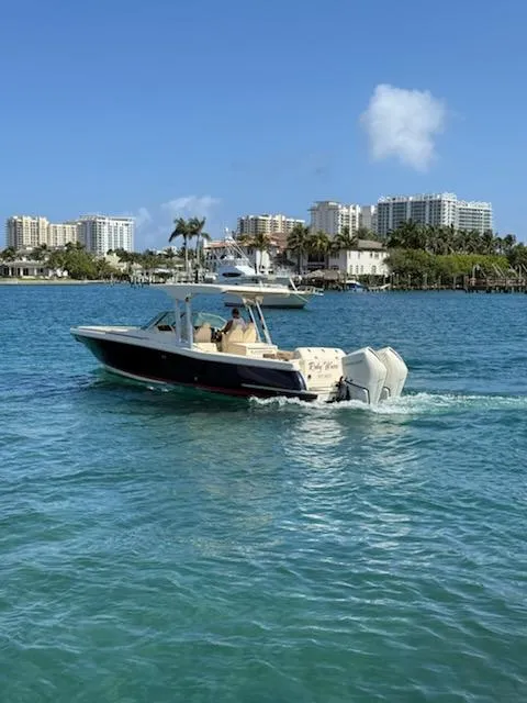 Slide: The Image of 2020 Chris-Craft Calypso 30 boat cruising on clear blue water near a city skyline. - 8