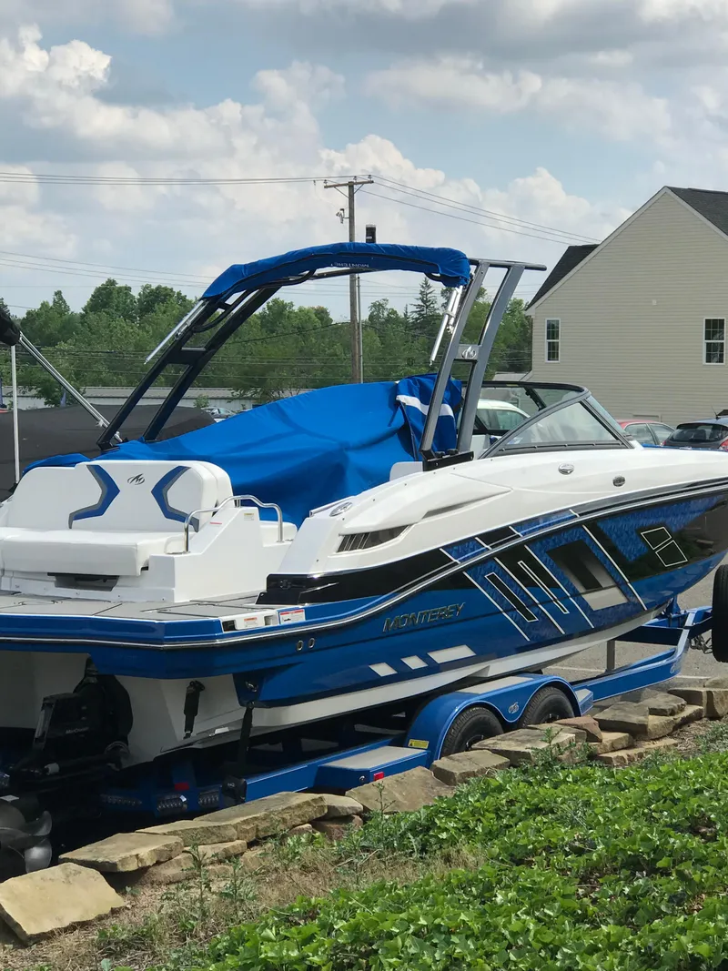 Slide: The Image of 2017 Monterey M6 boat with blue accents parked outdoors on a sunny day. - 45