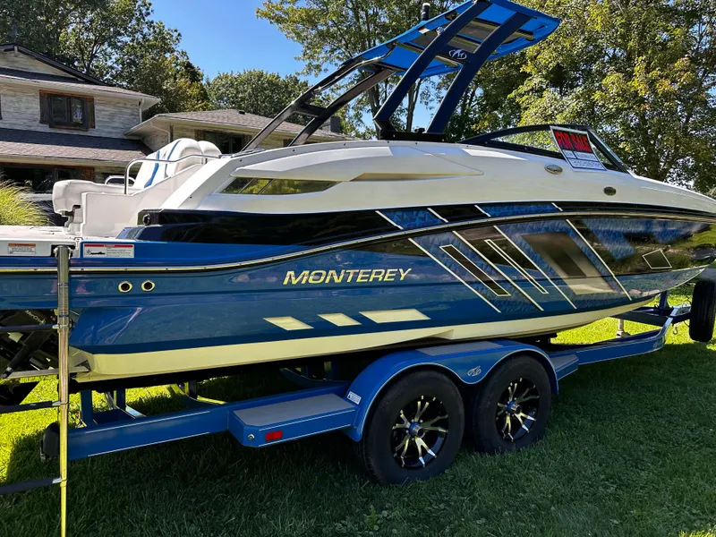 Slide: The Image of 2017 Monterey M6 boat on trailer, parked on grass, with house in background. - 7