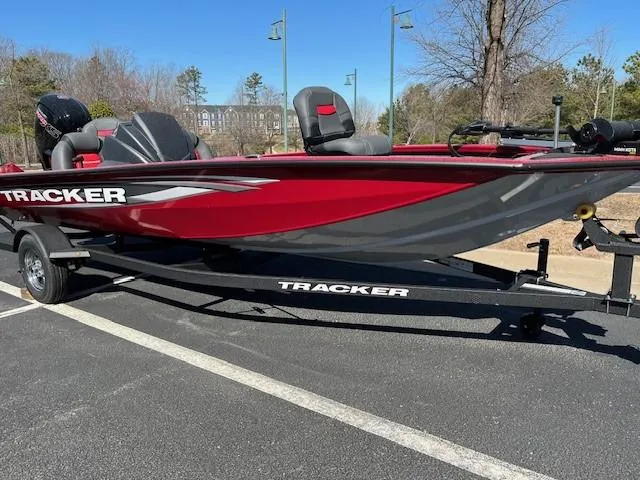 The Image of 2025 Tracker Pro Team 190 boat, red and gray, on a trailer in a parking lot. - 0