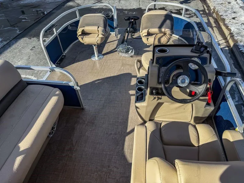 Slide: The Image of 2025 Sun Tracker Bass Buggy 16 XL Select pontoon boat interior with beige seating and steering console. - 2