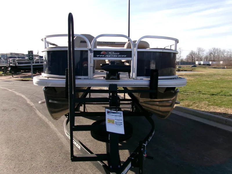 Slide: The Image of 2025 Sun Tracker Bass Buggy 18 DLX pontoon boat on trailer, parked outdoors. - 2