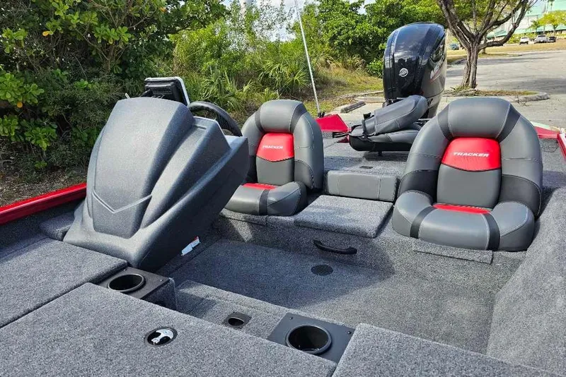 Slide: The Image of 2025 Tracker Pro Team 175 boat interior with seating and console, parked outdoors. - 4
