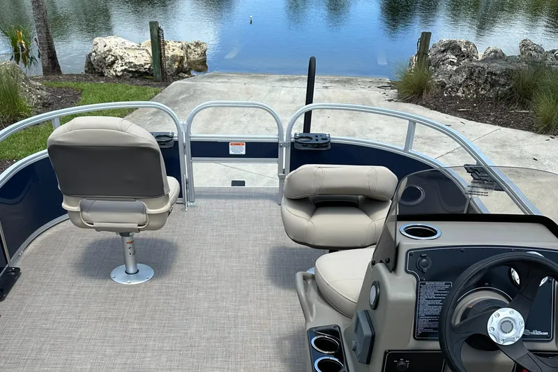 Slide: The Image of 2025 Sun Tracker Bass Buggy 16 XL Select pontoon boat interior by a lake. - 5