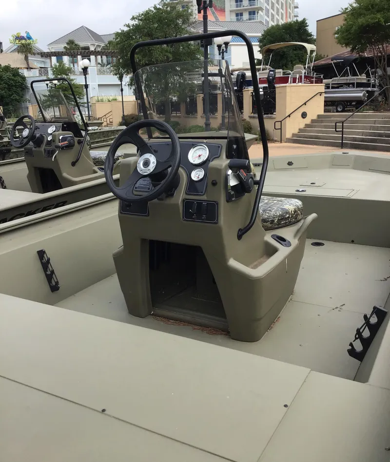 Slide: The Image of 2025 Tracker Grizzly 1860 CC boat with dual consoles, steering wheel, and gauges, docked outdoors. - 2