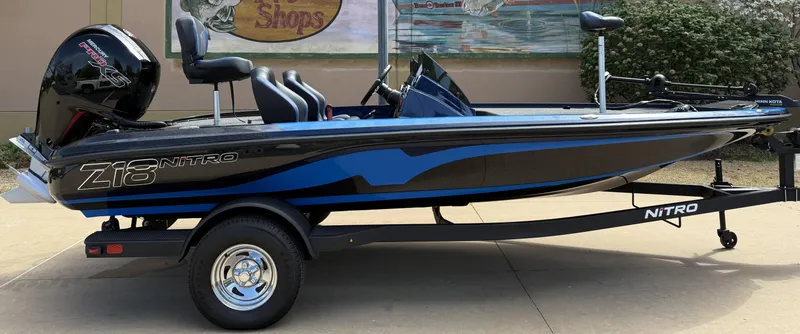 Slide: The Image of 2025 Nitro Z18 boat on trailer, black and blue design, parked outdoors. - 2