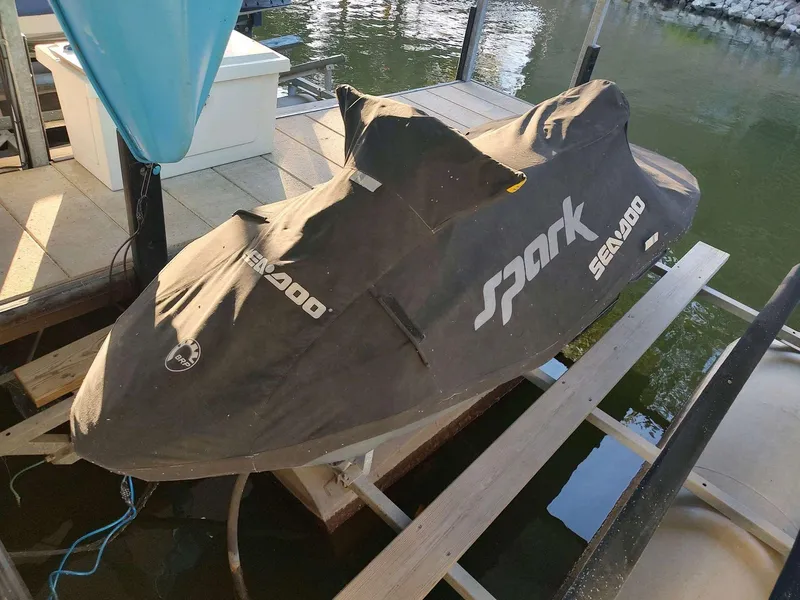 Slide: The Image of 2015 Sea-Doo Spark 2up jet ski covered on dock by water. - 2