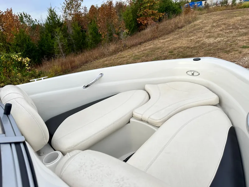 Slide: The Image of 2013 Tahoe Q4i boat interior with white seating, set against a grassy landscape. - 10