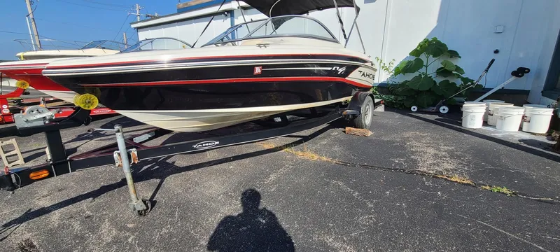 Slide: The Image of 2013 Tahoe Q4i boat on trailer, parked outdoors, with shadow and plants nearby. - 3