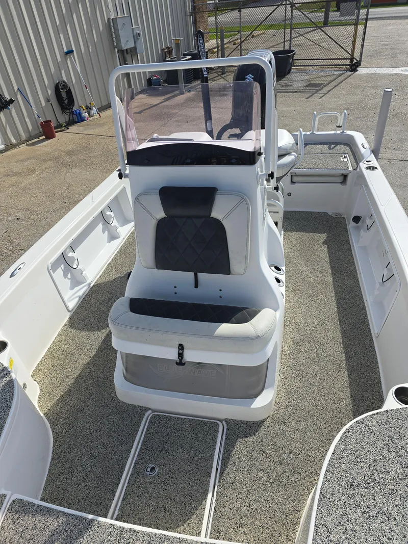 Slide: The Image of 2019 Blue Wave 2200 PureBay boat interior with seating and console, docked outdoors. - 10