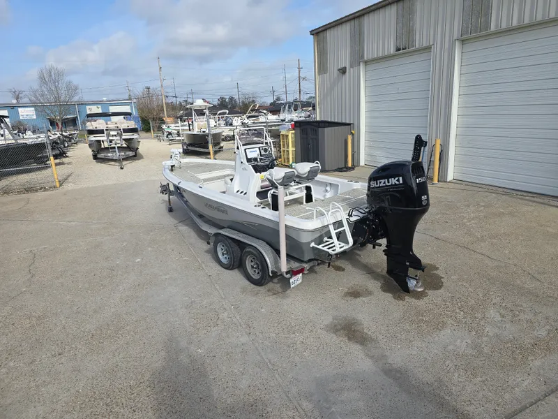Slide: The Image of 2019 Blue Wave 2200 PureBay boat with Suzuki engine on trailer, parked outside a warehouse. - 6