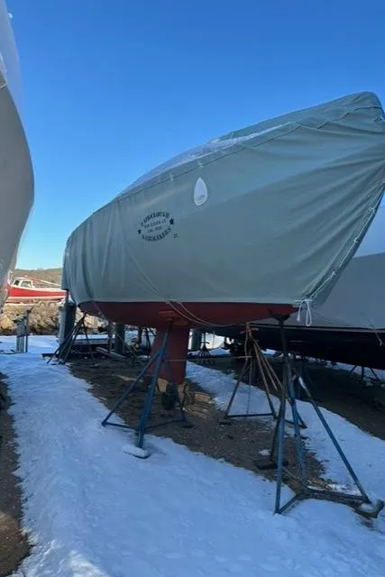 Slide: The Image of 2003 Alerion Express 28 sailboat covered and stored on stands in a snowy yard. - 18