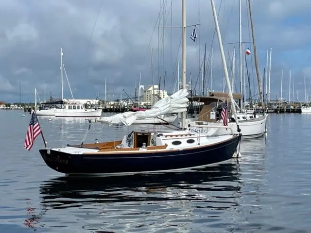 Slide: The Image of 2003 Alerion Express 28 sailboat docked in a marina, displaying an American flag. - 5