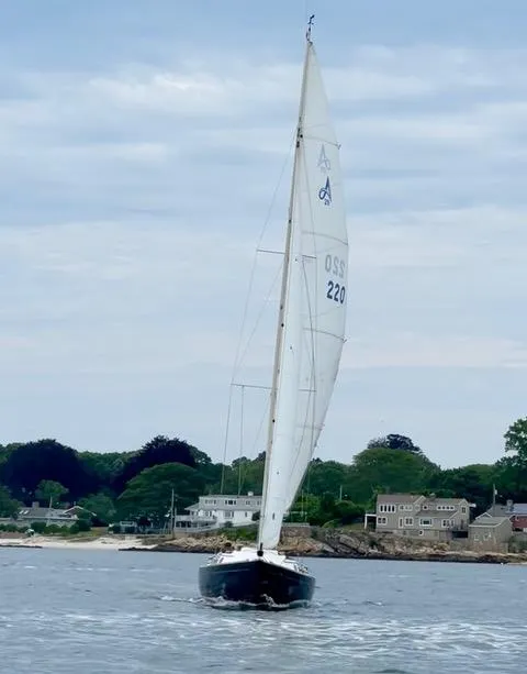 Slide: The Image of Alerion Express 28 sailboat from 2003 sailing near a coastal town. - 6