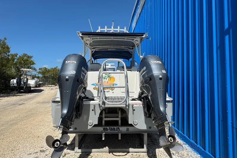 Slide: The Image of 2020 World Cat 28 DCX boat with dual outboard motors, parked near a blue building. - 3