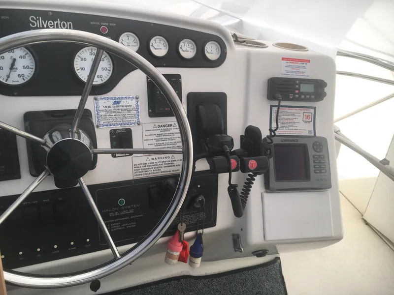 Slide: The Image of 1996 Silverton 372 Motor Yacht helm with steering wheel, gauges, and navigation equipment. - 22