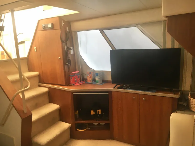 Slide: The Image of Interior of 1996 Silverton 372 Motor Yacht with TV, stairs, and wooden cabinetry. - 26