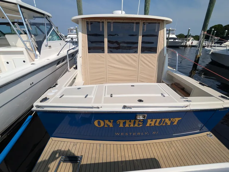 Slide: The Image of 2000 Hunt Yachts 28 Hardtop Express docked, rear view with "On The Hunt" text. - 10