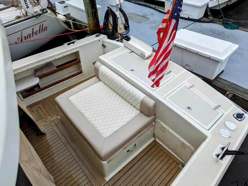Slide: The Image of 2000 Hunt Yachts 28 Hardtop Express with American flag, docked, featuring cushioned seating. - 13