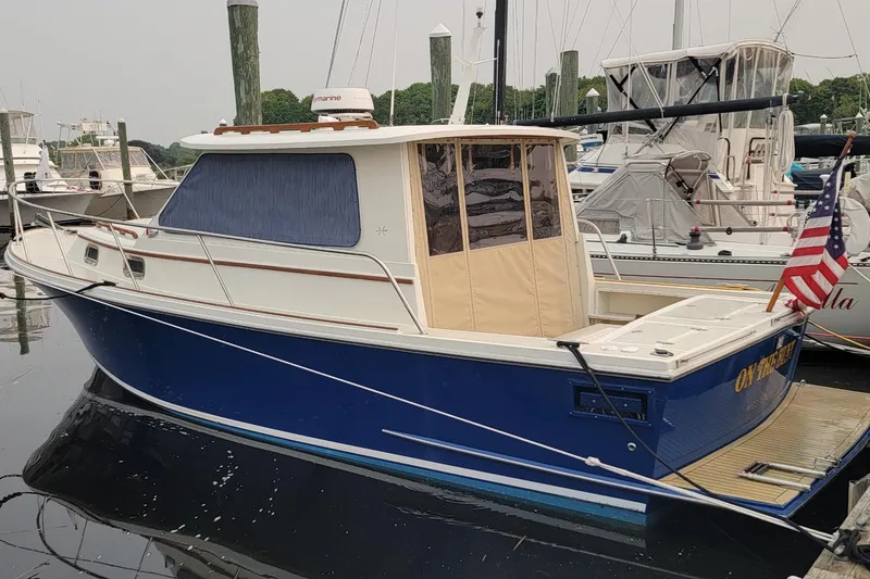 Slide: The Image of 2000 Hunt Yachts 28 Hardtop Express docked, featuring a blue hull and American flag. - 2