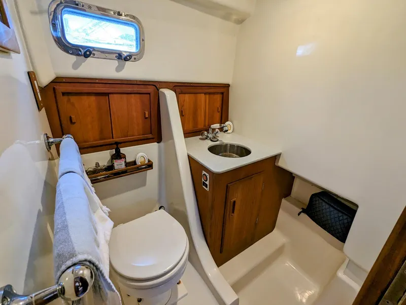 Slide: The Image of 2000 Hunt Yachts 28 Hardtop Express bathroom with wooden cabinets and porthole window. - 33