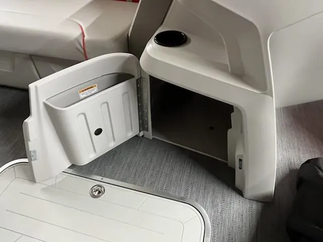 Slide: The Image of Interior storage compartment of 2025 Sweetwater 2286SB boat with open door and cup holder. - 13