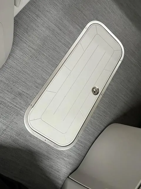 Slide: The Image of 2025 Sweetwater 2286SB boat storage compartment with secure latch on textured flooring. - 17
