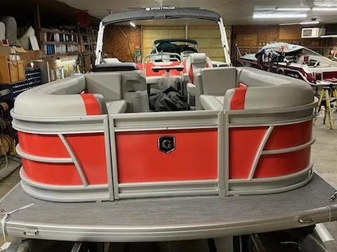 Slide: The Image of 2025 Sweetwater 2286SB pontoon boat with red and gray seating in a garage. - 2
