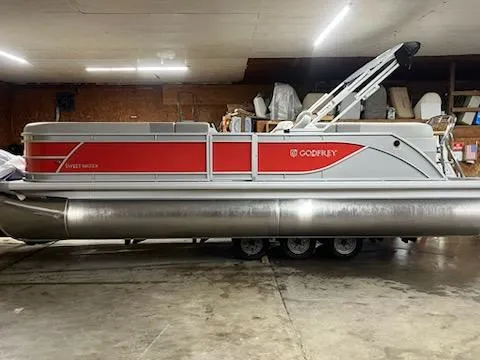 Slide: The Image of 2025 Sweetwater 2286SB pontoon boat in a garage, featuring red and gray design. - 3