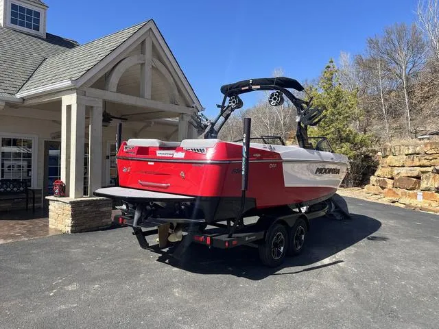 Slide: The Image of 2024 Moomba Mojo boat in driveway, red and white design, on a trailer. - 7