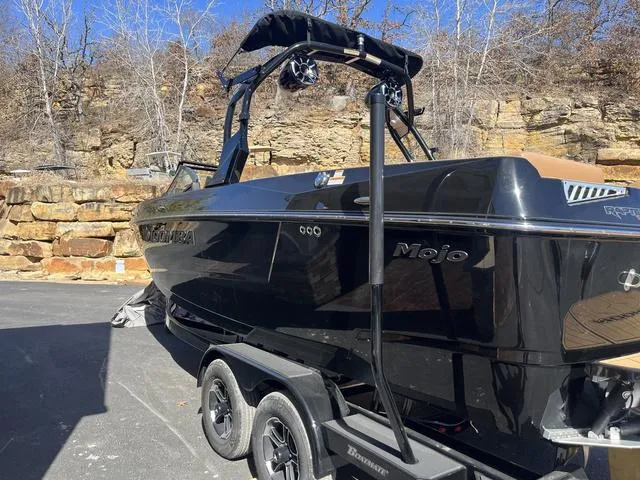Slide: The Image of 2024 Moomba Mojo boat on trailer, parked outdoors near rocky terrain. - 3